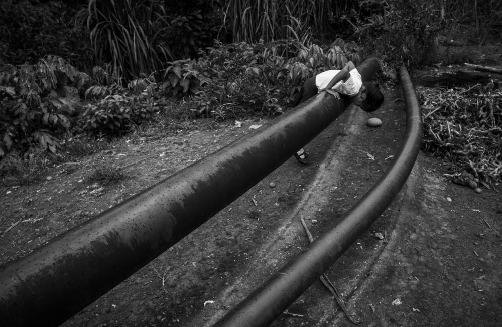 04/12/2018 - El Coca, Orellana Province in Ecuador
Five-year-old Genesis, plays amid Petroecuador’s oil pipes (formerly Texaco’s), running just a few meters away from her home in the outskirts of El Coca in the northern Ecuadorian Amazon. Genesis’ mother, Monica, has cancer, and one of her two other children was born with a congenital disease. Monica says that some nights the racket made by the oil pumping is unbearable. She also claims that five years ago, downstream, these pipes were responsible for an oil spill, and yet, Petroecuador’s staff deny this by assuring everyone these are just water pipes.
Picture taken with consent of the Genesis’ mother, Monica, while accompanying a member of the Union of People Affected by Texaco’s Oil Operations (UDAPT) during a medical round of her patients.