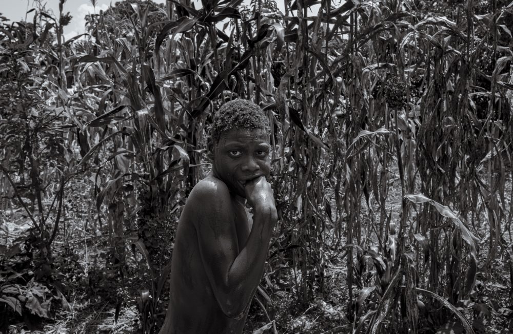 19 July 2023. Nabwigulu, Kamuli District, Uganda.  Perez Mwase cowers in the family maize field after being bathed by his mother Lovinsa Namwebya. 
19-year-old Perez lives with severe, category four, autism. Lovinsa tried for years to have her son’s condition diagnosed. Unable to deal with his aggression and hyperactivity, his parents tied him to a tree for 11 years. He was fed and toileted in the same place until late evening when he would join the family inside. Following the death of his father from suicide, Lovinsa struggled to care for Perez alone and he was moved to the Amaanyi Centre, a home and school for children with intellectual disabilities run by NGO Embrace Kulture, a two-hour drive away in Entebbe. While there he was formally diagnosed with severe, category four, Autism.  In November 2017 the family instigated a case challenging the Ugandan government and the Buyende Local Government with failure to provide early detection, rehabilitation, and habilitation services at the primary health care level for a person living with Autism. In a landmark decision in March 2022 the court ruled in favour of Perez on all counts.  The court found that the government’s failure amounted to a violation of his human rights; his right to health, right to equality and freedom from discrimination, and his right to human dignity provided for under the 1995 Constitution of the Republic of Uganda.