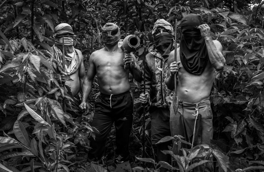 24/12/2016 Shariant community, Morona-Santiago Province, Ecuador.
Group of Shuar Indigenous people pertaining to the resistance in Nankints during the clashes between between Tsumtsuim community members and the military. They are waiting for the radio signal asking them to deploy to the Zamora River where the confrontation would took place.
Picture taken during a solo visit to the community. The group had previously welcomed me upon my arrival, and later agreed to be photographed posing with their weapons.  After expressing my concern about the visibility of their faces, which could expose them to persecution, each one covered up according to preference.